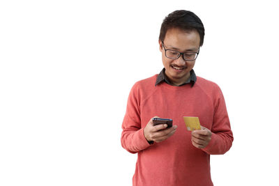 Mid adult man using smart phone against white background