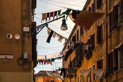 Low angle view of residential buildings against sky with laundry drying on clothesline 