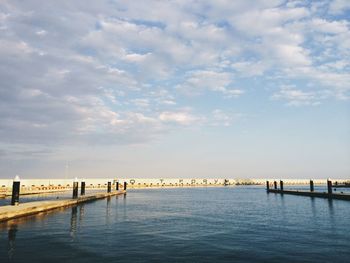 Pier on sea against cloudy sky