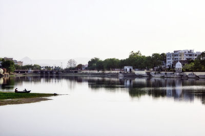 Scenic view of lake by buildings against clear sky