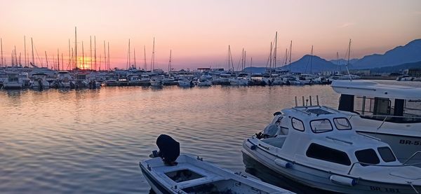 Sailboats moored at harbor against sky during sunset