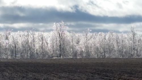 Snow covered landscape against cloudy sky