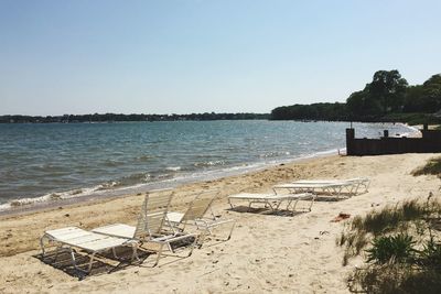 High angle view of empty lounge chairs at beach against clear sky