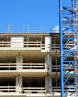 Low angle view of construction site against clear blue sky