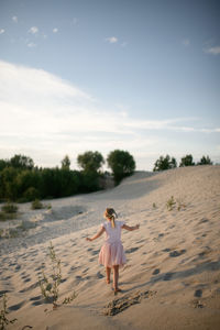 Rear view of woman walking at beach against sky
