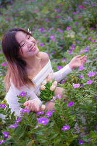 Portrait of young woman standing amidst flowers