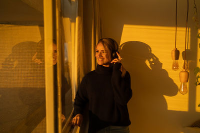 Portrait of young woman looking through window