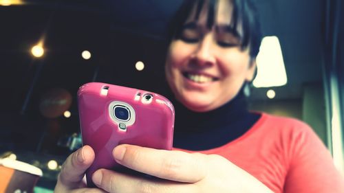 Smiling woman using smart phone at restaurant