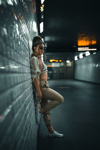 Side view of woman standing against illuminated wall