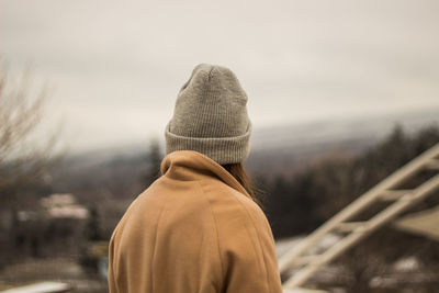 Rear view of woman in warm clothing against sky during winter