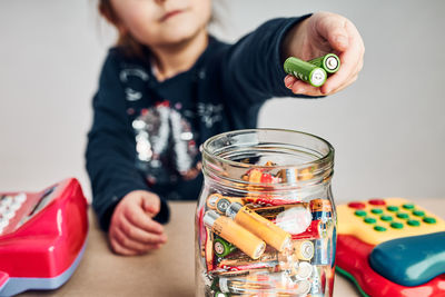 Little girl putting used batteries into jar for recycling. child separating waste. batteries only