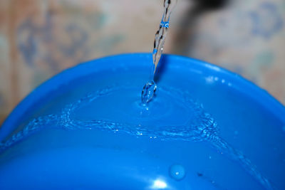 Close-up of drop falling on blue water