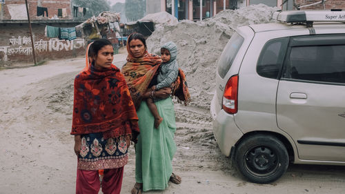 Woman standing by car on street in city