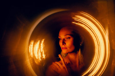 Dancer poses on a dark background in a bright halo.