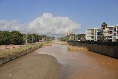 Scenic view of river by buildings against sky