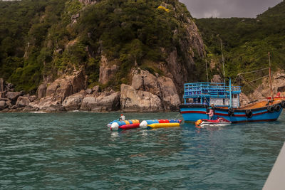 Boats moored on sea against mountain