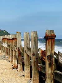 Wooden posts on beach against sky