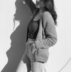 Side view of woman standing against wall