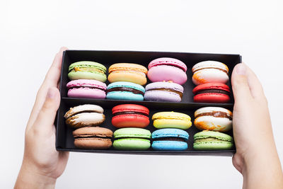 Midsection of person holding multi colored candies against white background