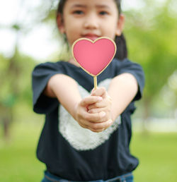 Close-up portrait of girl holding heart shape candy