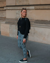 Portrait of young woman standing against wall