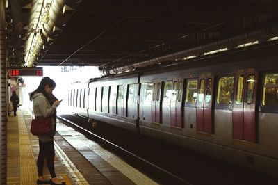 Rear view of woman standing at railroad station platform