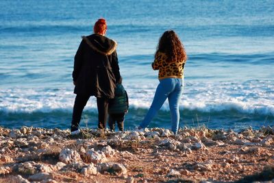 Rear view of women and child standing at beach