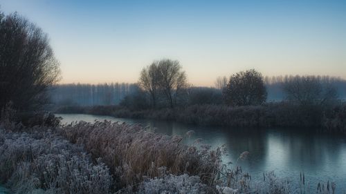 Scenic view of lake against sky during winter