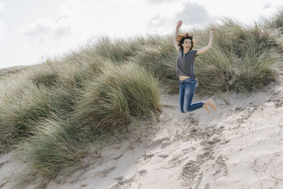 Happy woman jumping in beach dune