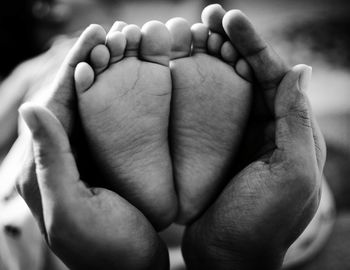 Cropped image of person holding baby feet