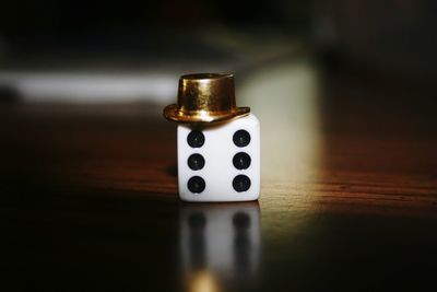 Close-up of dice with toy hat on wooden table