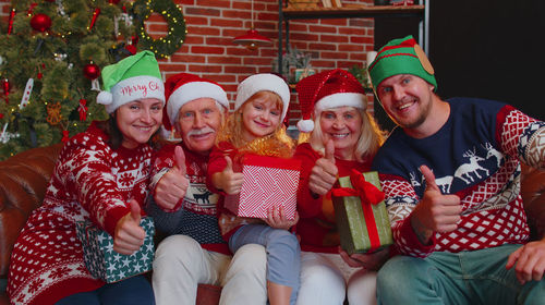 Cheerful family sitting on sofa against christmas tree at home