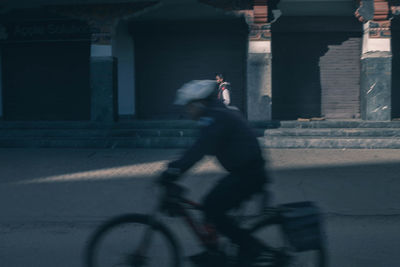 Blurred motion of man riding bicycle on street