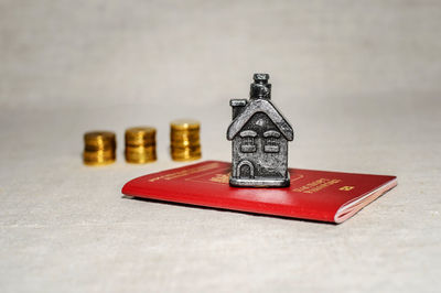 Close-up of coins with passport and model home on table