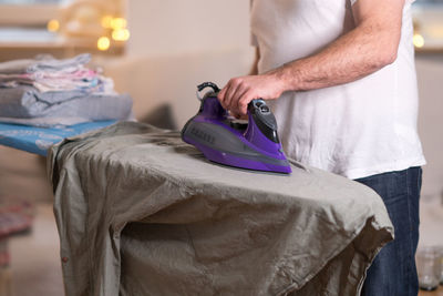 Midsection of man ironing shirt on board
