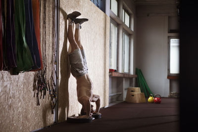 Young athlete doing handstand in gym