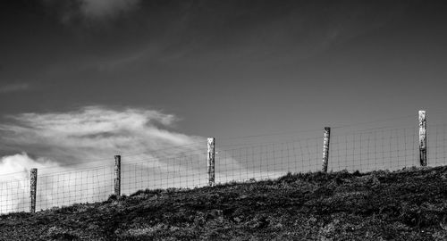 Fence on hill against sky