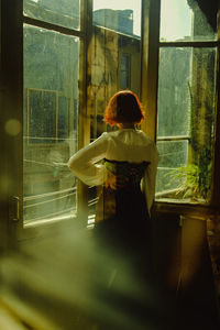 Rear view of woman standing by window