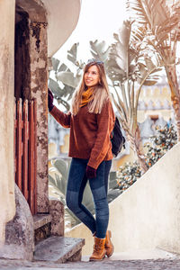 Smiling young woman standing by building