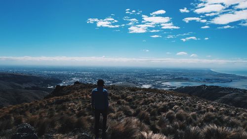 Rear view of man standing by sea against sky