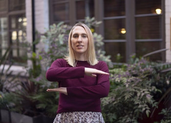 Portrait of smiling young woman standing against plants