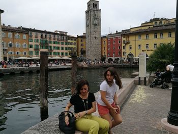 Woman sitting in city against sky