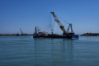 Cranes at commercial dock against clear sky