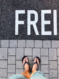 Low section of man standing on footpath by text