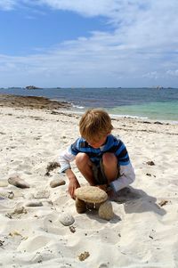 Boy playing with pebble stones at beach