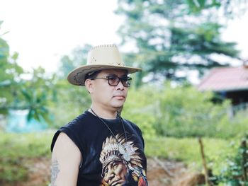 Man wearing hat while standing against trees