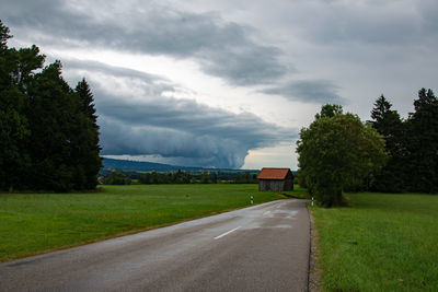 Road amidst field against sky