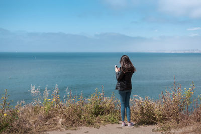 Full length of woman standing on sea shore against sky