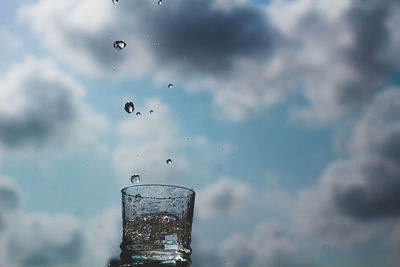 Close-up of water drops on glass against the sky