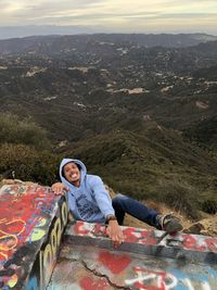 Portrait of smiling young woman sitting on mountain